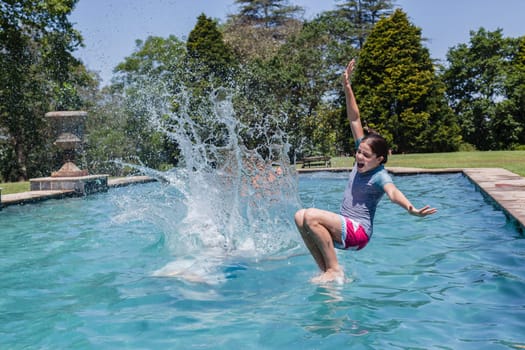 Girls running jumping into home  swimming pool summer playtime
