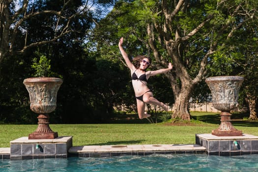 Girl running jumping into home swimming pool summer playtime