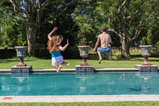 Girls boys running jumping into home  swimming pool summer playtime