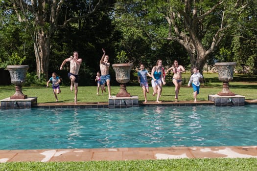 Girls boys teenagers young running jumping into home  swimming pool summer playtime