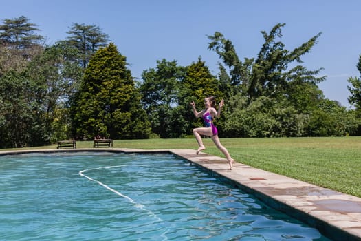 Girl running jumping into home swimming pool summer playtime