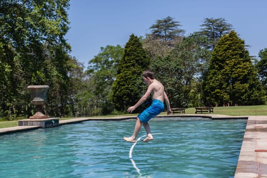 Boy running jumping diving into home  swimming pool summer playtime