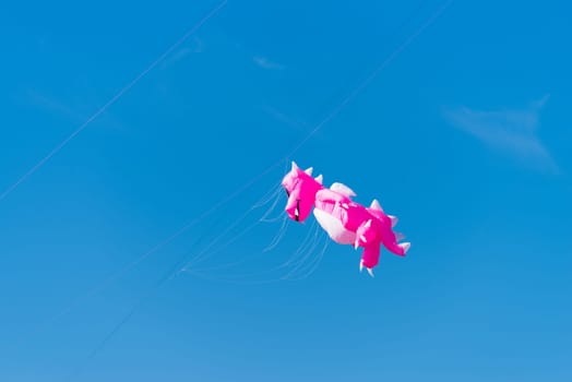 pink dragon shaped kite against a blue sky