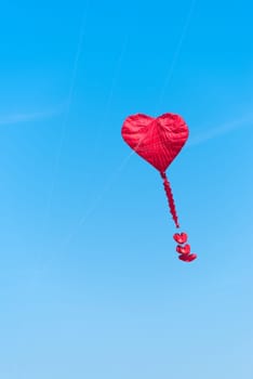 red heart shaped kite against a blue sky