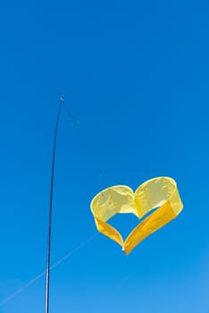 yellow heart shaped kite against a blue sky
