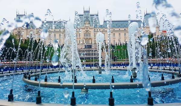 The gush of water of a fountain in front of a beautiful cultural palace in Iasi city, Romania