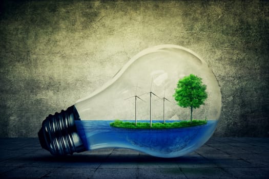 Light bulb as a micro planet with blue water and a island with green grass and tree growing inside. Windmill generator as the symbol of energy conservation and eco friendly concept and on gray background.