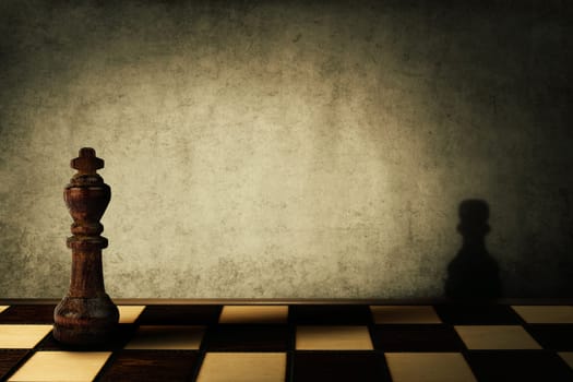 King chess piece casting a shadow of a pawn on a concrete wall. Complex and mismanagement concept. Magical transformation.