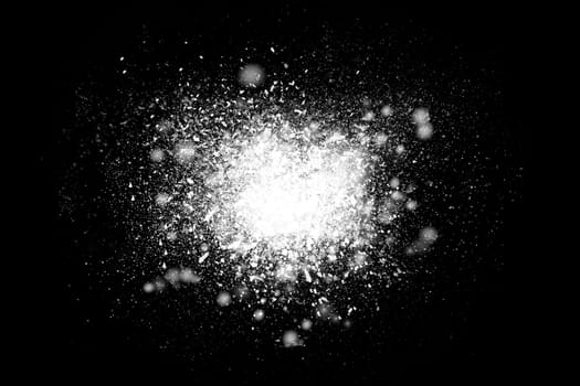 Freeze motion of white powder exploding, isolated on black, dark background. Abstract design of dust cloud. Particles explosion, screen saver wallpaper with copy space..
