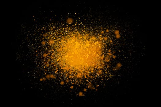 Freeze motion of colorful yellow powder exploding isolated on black dark background. Abstract design of color dust cloud. Particles explosion screen saver, wallpaper, brush. Universe creation concept
