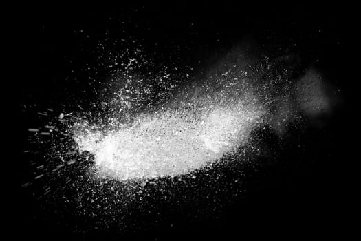 Freeze motion of white powder exploding, isolated on black, dark background. Abstract design of dust cloud. Particles explosion, screen saver wallpaper with copy space.