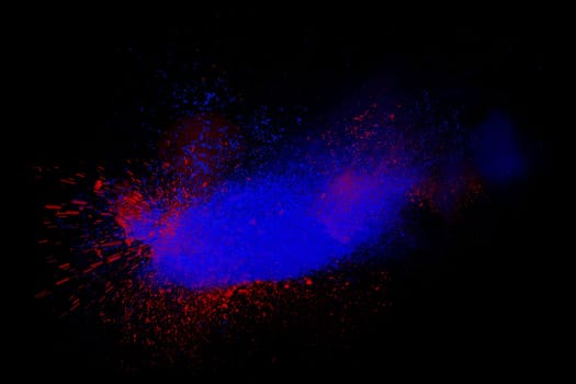 Freeze motion of red and blue powder exploding, isolated on black, dark background. Abstract design of dust cloud. Particles explosion, screen saver wallpaper with copy space. Vivid colorful ash