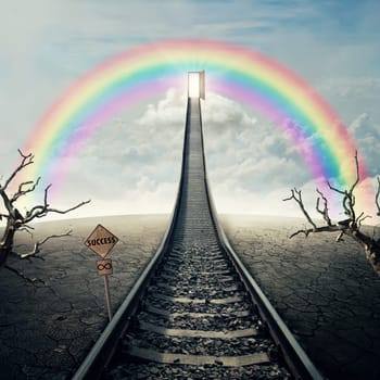 Railway of opportunity along a cracked desert ground with dry trees, going up as a staircase to a opened door over the rainbow in the sky. Road to success symbol. Business plannig concept