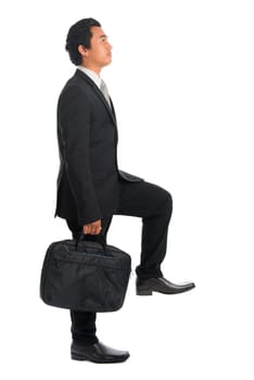 Full body attractive young Southeast Asian businessman stepping up stair case, isolated on white background. Asian malay male model.