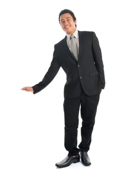 Full body portrait of young Southeast Asian businessman hand leaning on invisible object, standing isolated on white background.