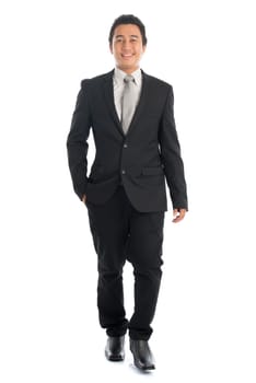 Full length front view portrait of attractive young Southeast Asian businessman walking, isolated on white background.