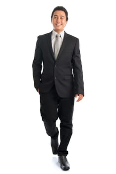 Full length front view portrait of handsome young Southeast Asian businessman walking, isolated on white background.