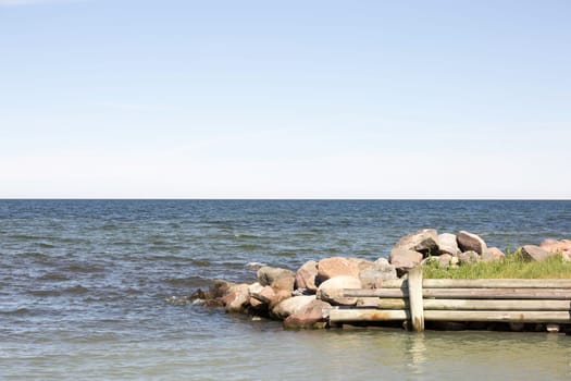 Breakwater with Ocean and a partly cloudy sky.