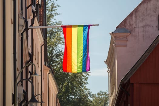 The  Rainbow Flag on a Flagpole by buildings in Visby, Gotland, Sweden.