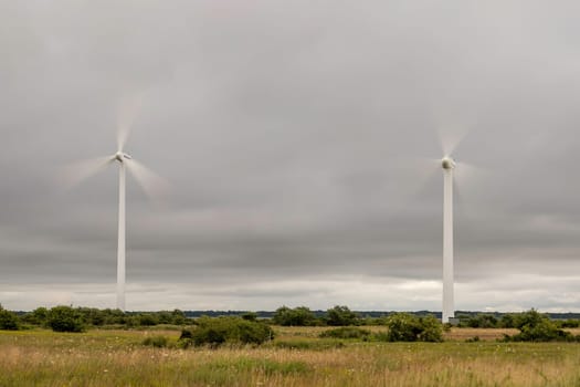 Wind Power Stations Spinning in Green Field.