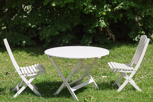 White Garden Chairs and Table with green grass.