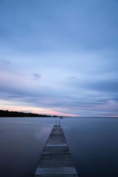 Pier into the Ocean at sunset with clouds.