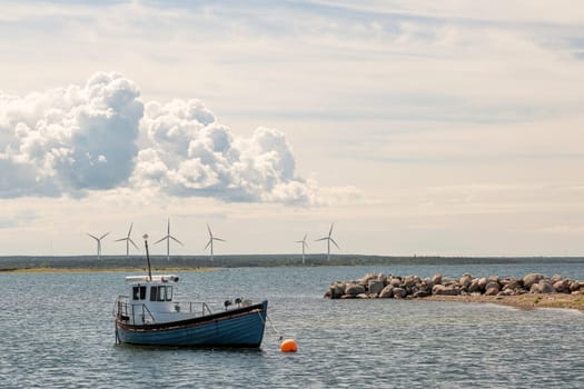 Fishing Boat by Wind Power Stations and a partly cloudy sky.