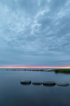 Rowboat by Ocean at Sunset with a partly cloudy sky.