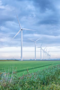 row of wind turbines in early morning in a flat dutch landscape