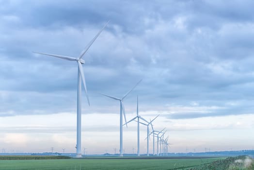 row of wind turbines in early morning in a flat dutch landscape