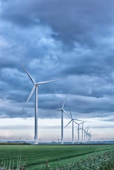 row of wind turbines in early morning in a flat dutch landscape