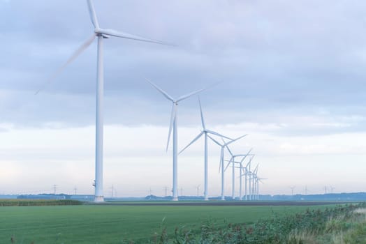 row of wind turbines in early morning in a flat dutch landscape