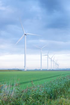 row of wind turbines in early morning in a flat dutch landscape