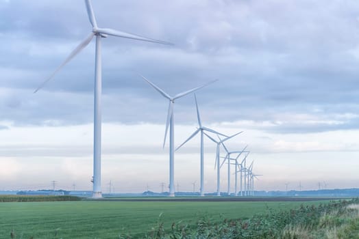 row of wind turbines in early morning in a flat dutch landscape