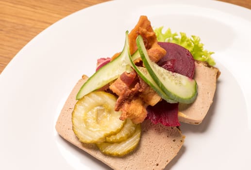 Danish specialties and national dishes, high-quality open sandwich, Liver Pate with bacon pickled cucumber, beetroot and cucumber served on a plate ready for eating