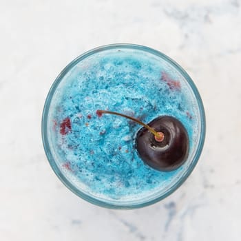 Blue cherry smoothie on a white concrete background. Square cropping