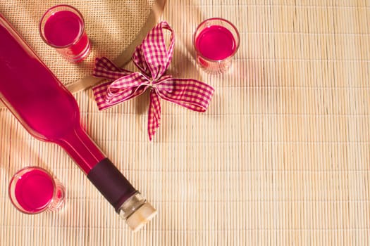 Pink alcoholic drink is in bottle and glasses on natural background.