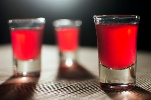 Three glasses of red alcohol are on the table.