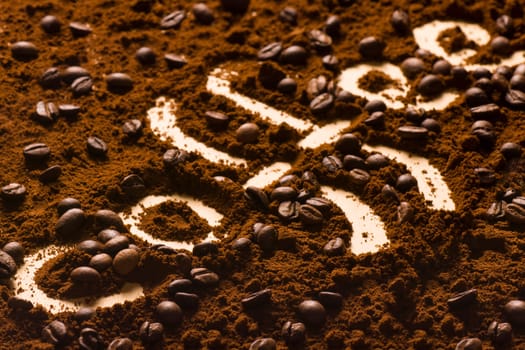 Letters of coffee are written from coffee powder and beans.