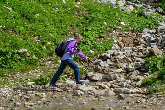 European woman crosses a stream on a hike in the Allgäu