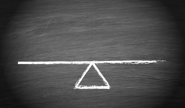 Seesaw or scale in balance on chalkboard background