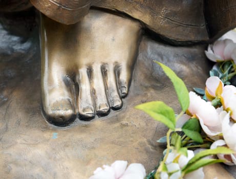 Foot of bronze statue with flowers