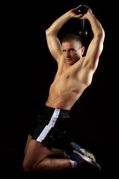 The man exercises his triceps  on black background.