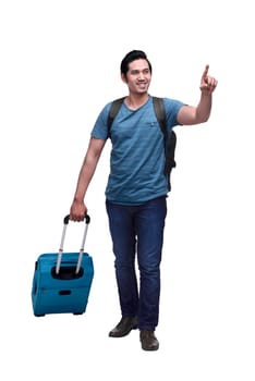 Happy asian traveler with backpack and suitcase pointing something isolated over white background