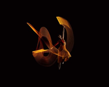 Beautiful ballerina dancing with lights effect over black background