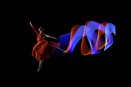Beautiful ballerina dancer with colorful lights effect over black background