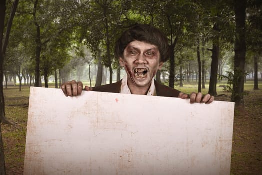 Spooky asian zombie man in suit with empty banner on the forest
