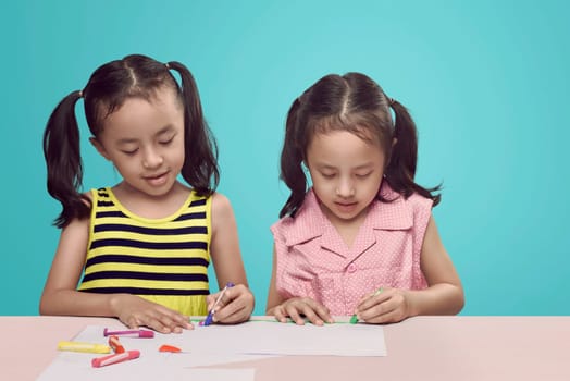Creative two asian kid with crayon drawing on the desk over bright background