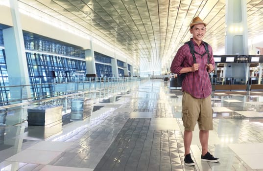 Traveler asian man wearing hat with backpack in the airport terminal