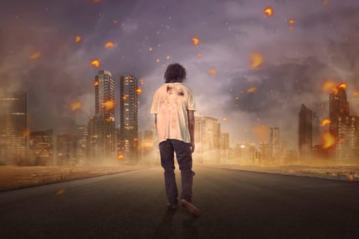 Back view of walking zombie male on the burning city
